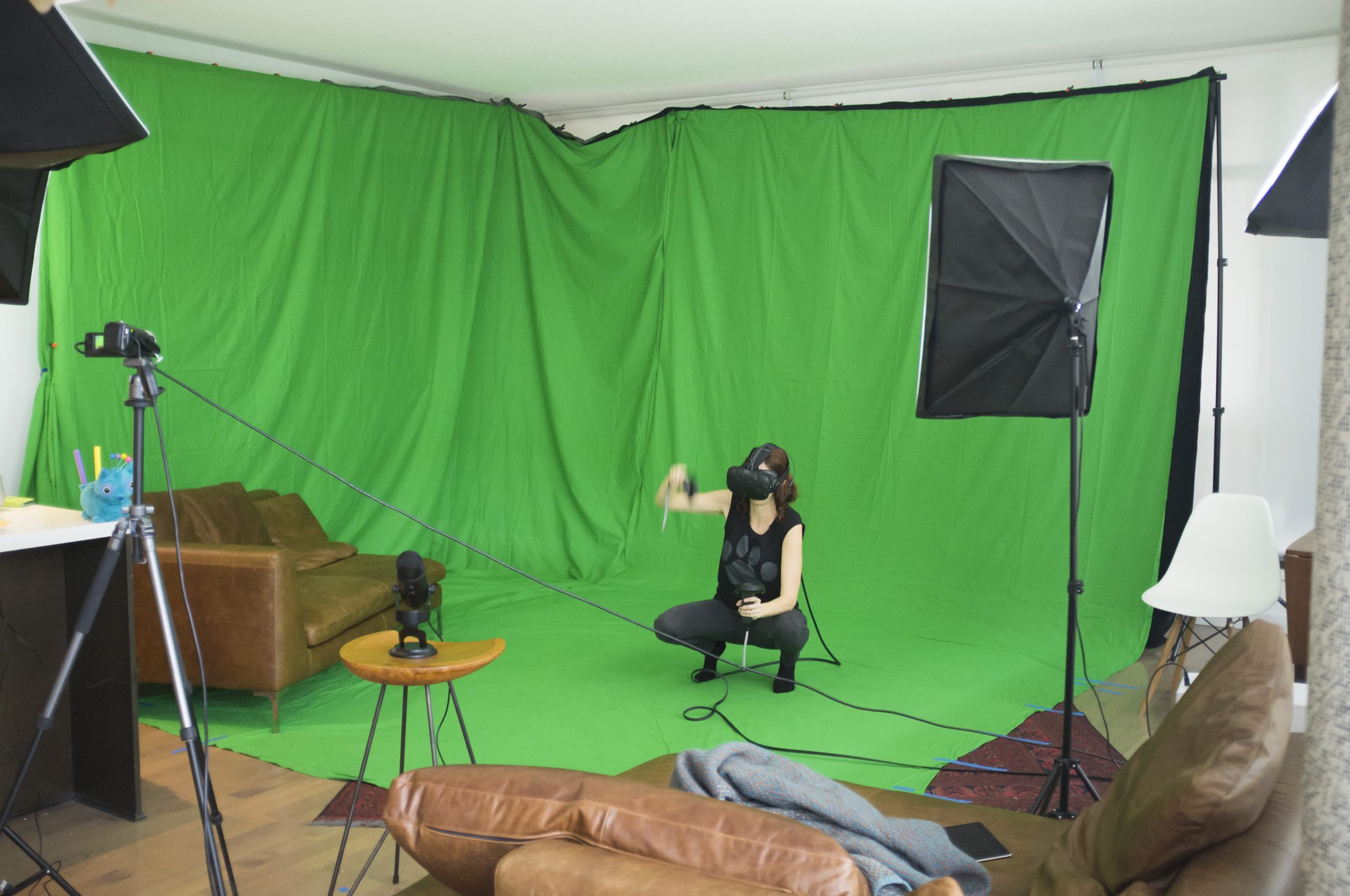 Un studio de création avec fond vert, softbox d'éclairage et caméra sur trépied, installé dans un espace lumineux